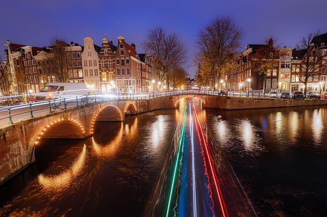 Imagem mostra foto noturna de amsterdam que é uma das melhores cidades da Holanda para uma viagem ou morar